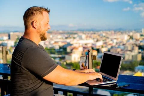 Man working on a computer in a cafe with a beautiful view Stock Photos