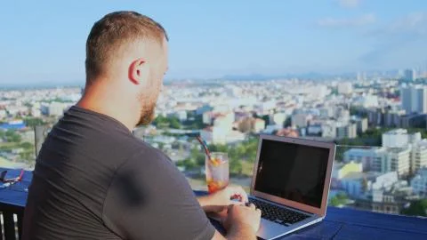 Man working on a computer in a cafe with a beautiful view Stock Photos