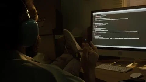 Man working on computer with code in a dark room Stock Photos