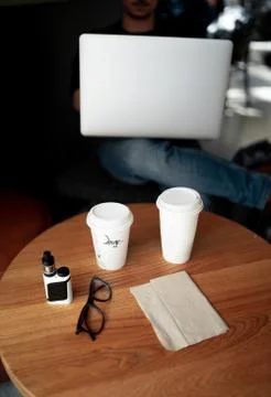Man working with computer at a coffee shop with cup and glasses on the table Foto stock