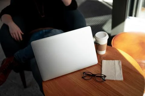 Man working with computer at a coffee shop with cup and glasses on the table Stock-Fotos