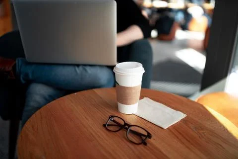 Man working with computer at a coffee shop with cup and glasses on the table Foto stock