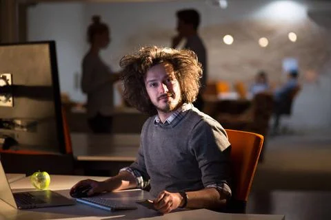 Man working on computer in dark office Young man working on computer at ni... Stock-Fotos