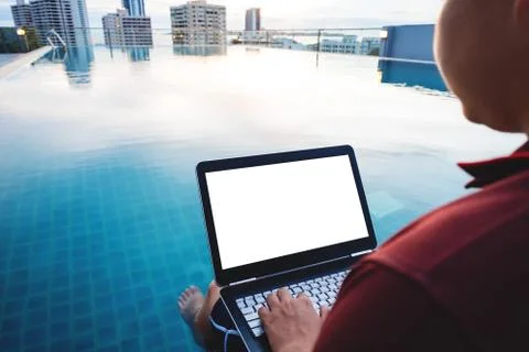 A man working on computer laptop, at poolside in the city. Clipping path Stock Photos