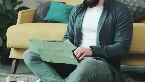 Man working at the computer with a lot of reminder notes, sitting near sofa. Stock Footage 154905276
