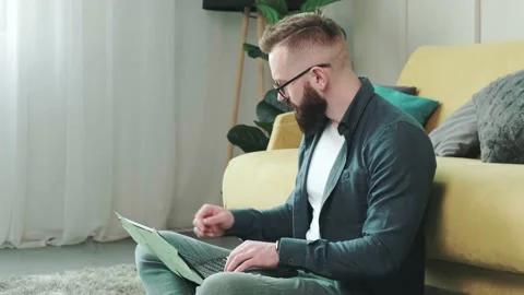 Man working at the computer with a lot of reminder notes, sitting near sofa. Stock Footage 155404139