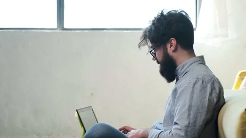 Man working at the computer with a lot of reminder notes, sitting near sofa. Stock Footage 155404469