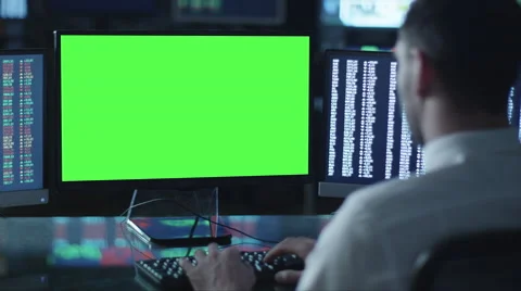 Man is working on a computer with mock-up green screen in a dark office Stock Footage 59975363