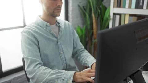 Man working on computer in a modern office with plants and bookshelves, wea.. Stock Footage 305543702