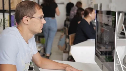 Man is working at a computer in a noisy and crowded office. Stock Footage 81792244