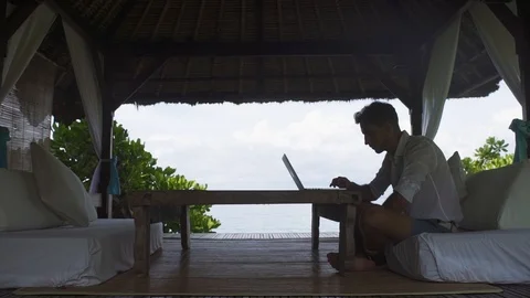 Man working at a computer by the ocean Stock Footage 99586336
