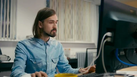 Man is Working at the Computer in the Office as a Designer or Programmer Stock Footage 90823525