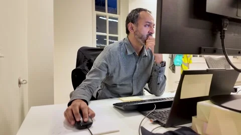 Man is working at a computer in an office late at night He is using a mouse and Stock Footage 328343411