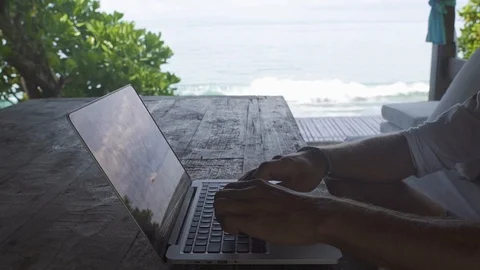 Man working at a computer by the sea, static frame, close up Stock Footage 99400959
