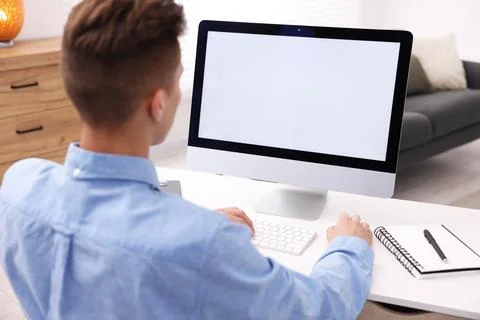 Man working on computer at white desk in office. Mockup for design Stock Photos