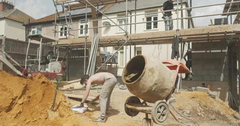 Man working on a construction site next to a cement mixer Stock Footage 246382416