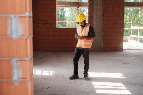Man Working In Construction Site Smiling And Using Smartphone Stock-Fotos