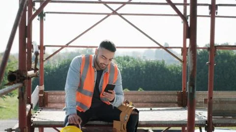 Man Working In Construction Site Smiling And Using Smartphone Stock Photos