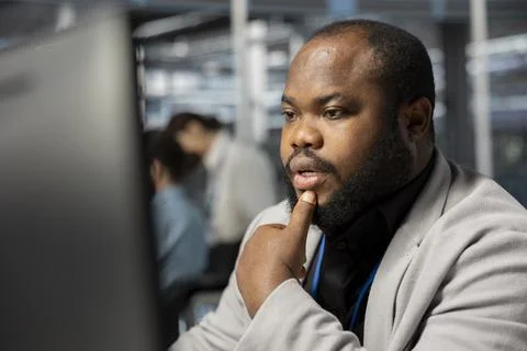 Man working in data center analyzing software logs metrics on PC Stock Photos
