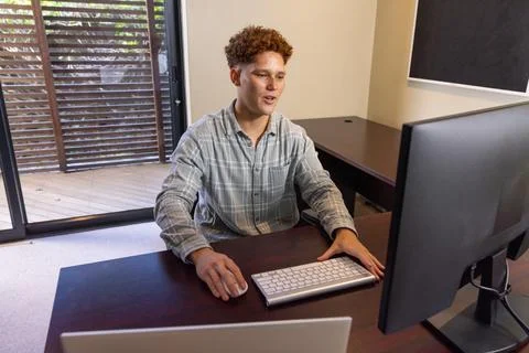Man working at desk on computer while typing on keyboard, using mouse in home Foto stock