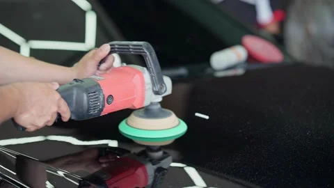 A man working in the detaling studio polishes the car, smearing polishing paste Stock Footage 239665472
