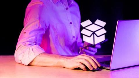 Man working devices with illuminated open box icon in purple ambiance Stock Photos