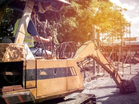 Man working on a digger loading trucks at construction site. Stock Photos