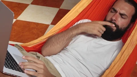 Man working on digital laptop, thinking and find solution in hammock at home Stock Footage 99437476