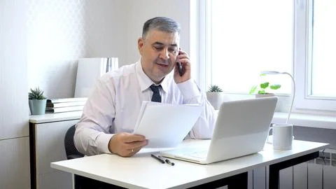 Man Working with Documents and Talking on Phone in Office 写真素材