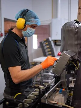 Man working with an electronic beer packaging machine. Stock Photos
