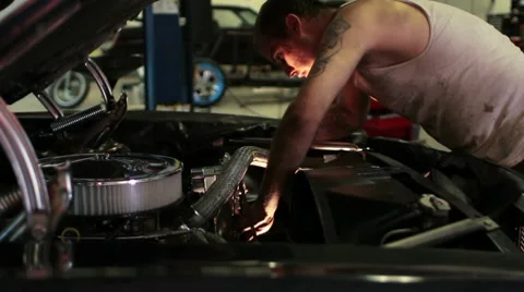 Man working on the engine of a classic car in a shop Stock Footage 8612705