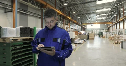 A man is working in a factory with a digital tablet, he is dressed in a blue Stock Footage 91643002