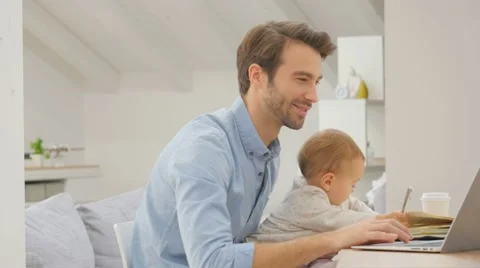 Man working form home on laptop, baby on lap Stock Footage