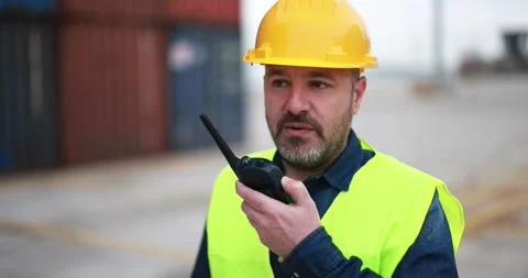Man working at freight terminal port while using walkie talkie Stock Footage 179971070