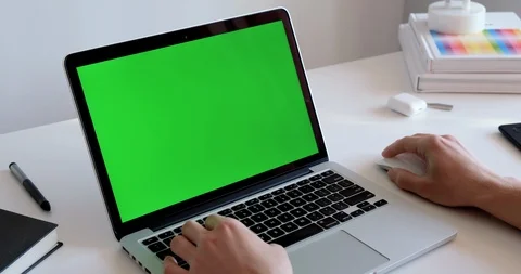 Man working in front of a laptop in a white modern office with a green screen Stock-Footage 127316540