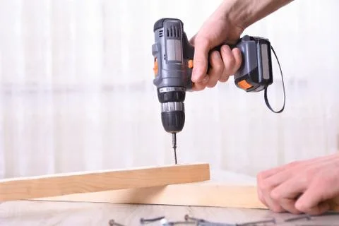 Man is working with furniture assembly using electric screwdriver in new hous Stock Photos