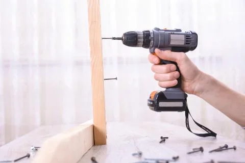 Man is working with furniture assembly using electric screwdriver in new hous Stock Photos