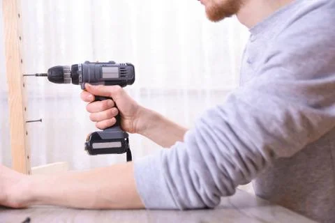 Man is working with furniture assembly using electric screwdriver in new hous Stock Photos