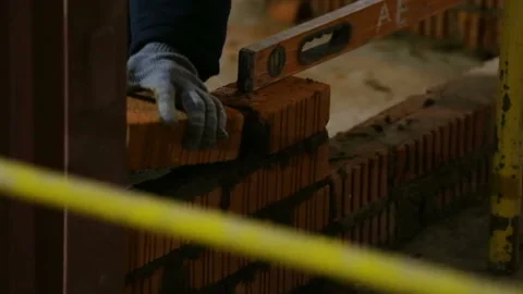 A man in working gloves makes brickwork with a spatula on the construction site. Video stock 93273156