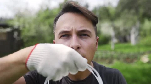 Man in working gloves puts on the resperator in slow motion outdoors Stock Footage 89467145