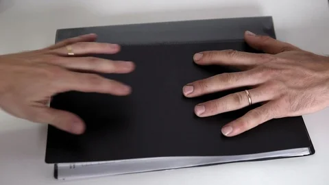 A man with working hands puts a folder on the table and moves it to another man Stock Footage 122264471