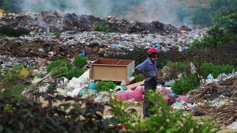 A man working in heap of garbage and watching it burn. Stack of different Video stock 157085070