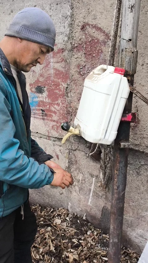 A man working in heavy industrial work washes his dirty hands with water from a Stock Footage 322733584