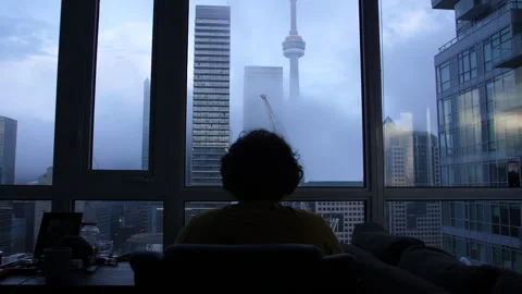 A man working at his apartment desk overlooking the Toronto CN Tower 스톡 동영상 255199072