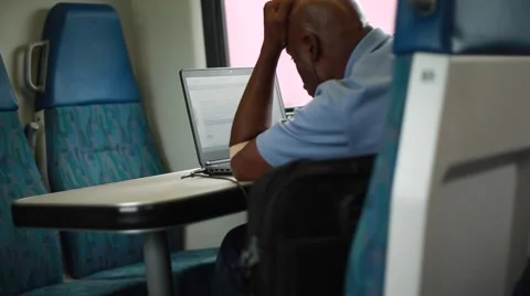 Man working on his computer from inside of a moving train Stock Footage 58980737