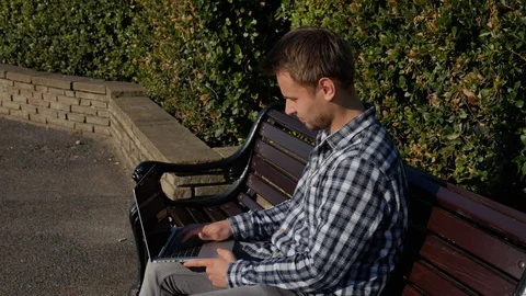 Man working on his computer sat on a bench Video stock 97022723
