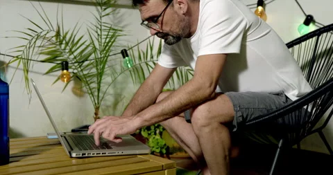 A man is working on his laptop on the balcony at night Vidéo 336312824