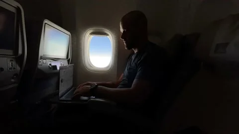 Man working on his laptop while flying in the airplane Stock Footage 154612656