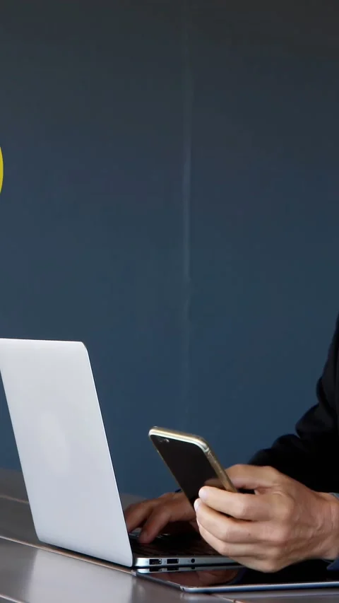 Man working on his laptop while browsing on his phone 4k Vidéo 341952823