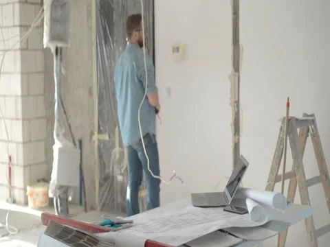 Man working on his project about new flat and measuring walls, steadycam shot Stock Footage 76492445
